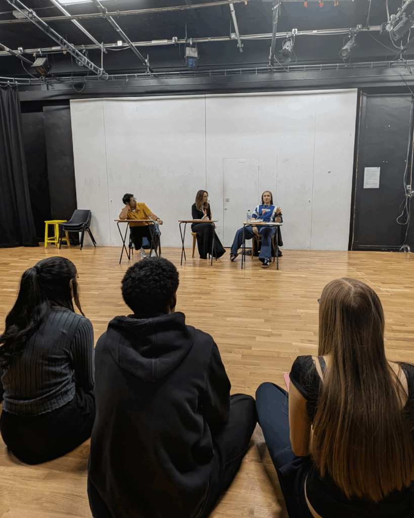 Three people sat at a table in front of the class