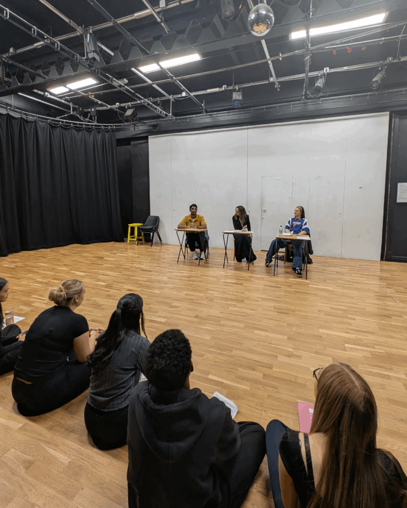 Three people sat at a table in front of the class